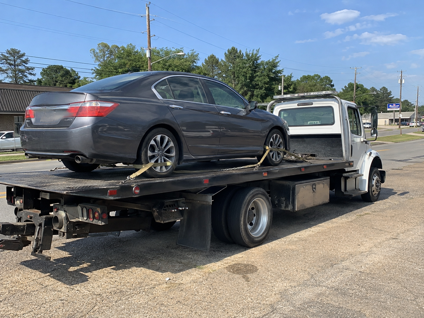 Gray sedan loaded and secured on a flatbed for towing