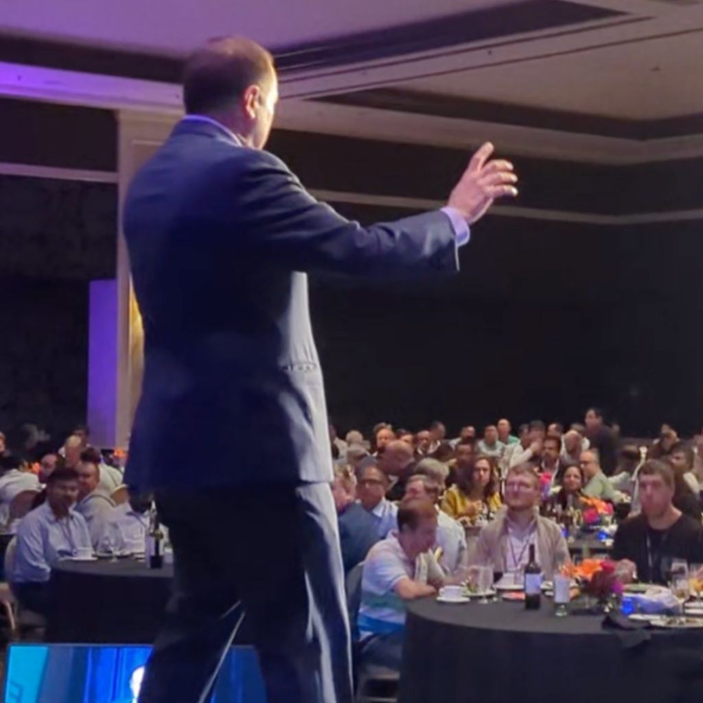 Corporate magician David Martinez stands on stage in front of a crowd at a large event