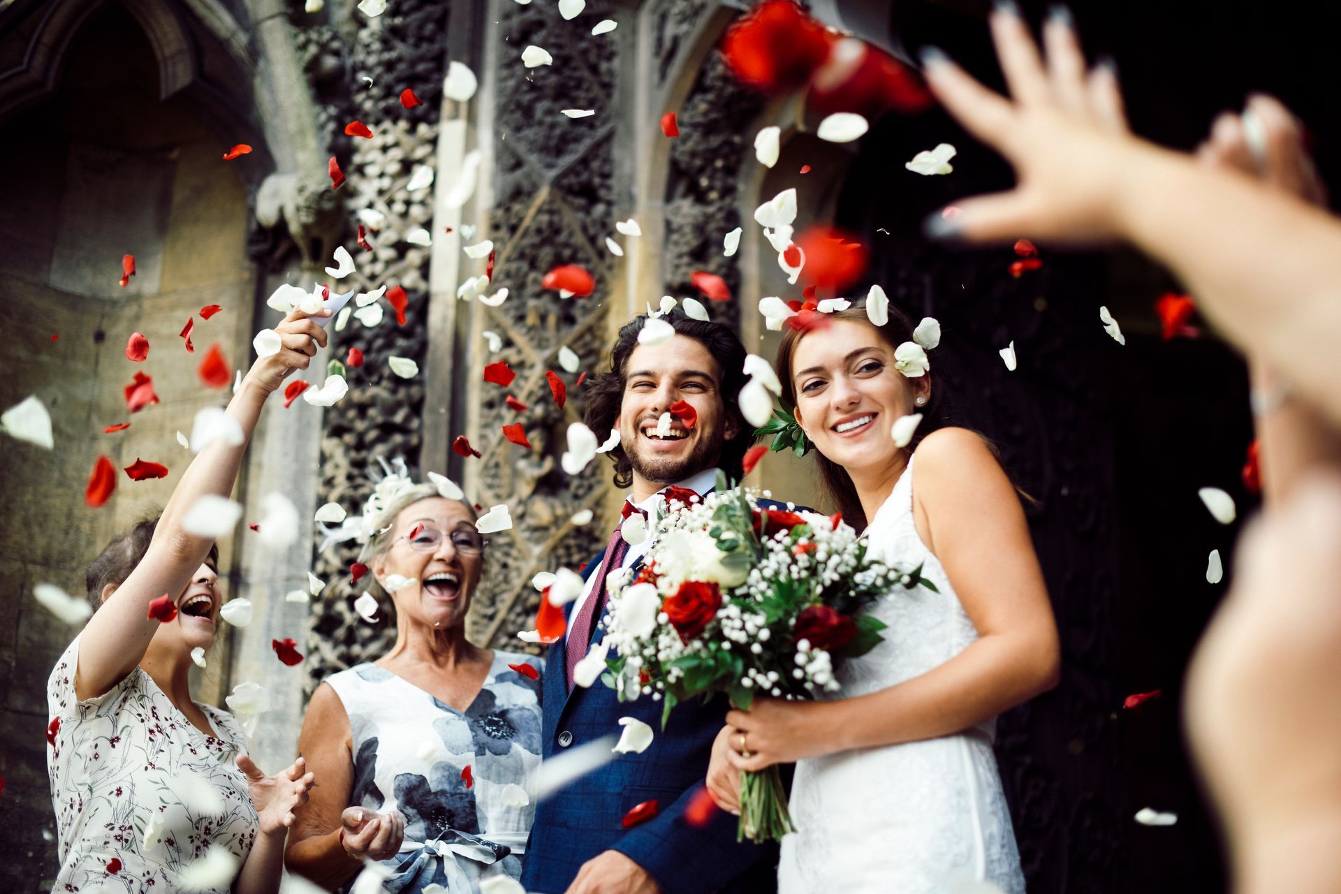 Rose petals are thrown into the air at a wedding