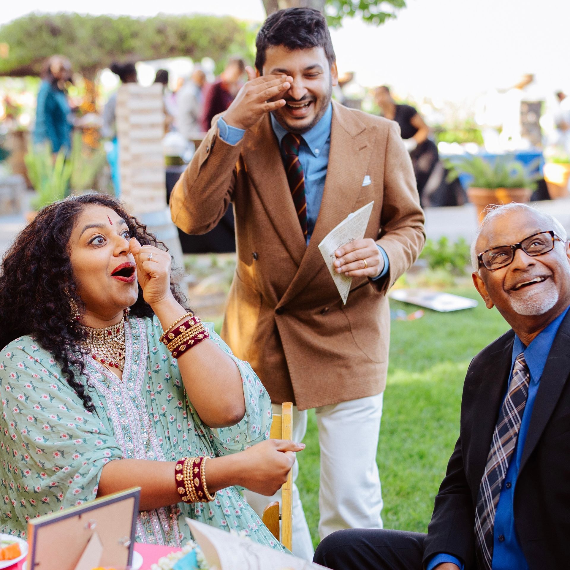 Three guests react with laughter and surprise at a trick performed by wedding magician David Martinez