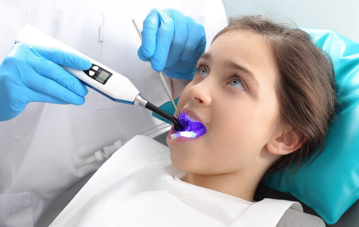 A little girl is getting her teeth examined by a dentist.