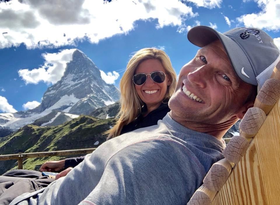 Couple smiling on a lounge chair with the Matterhorn mountain behind them under a bright sky