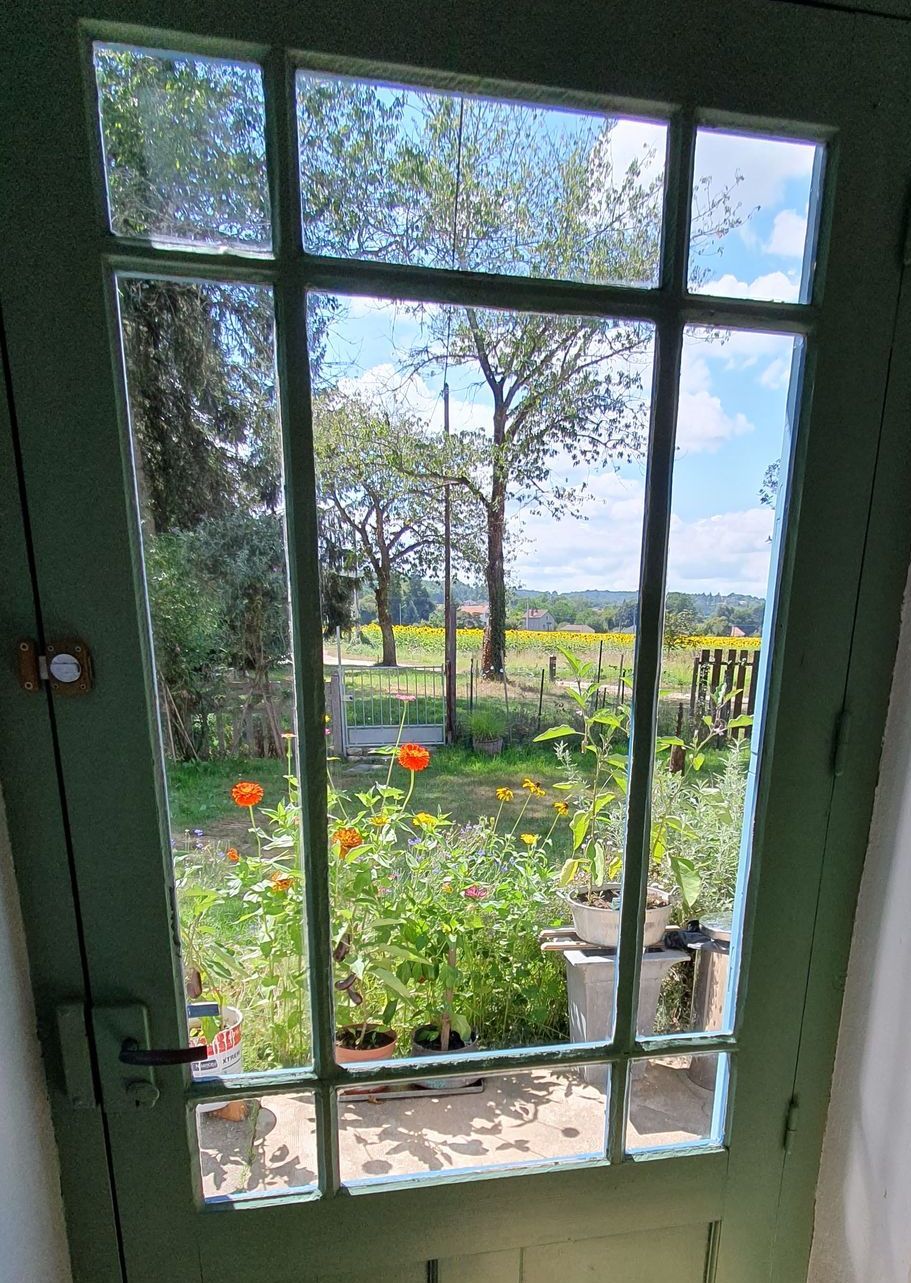 Une fenêtre avec vue sur un jardin des arbres et les champs