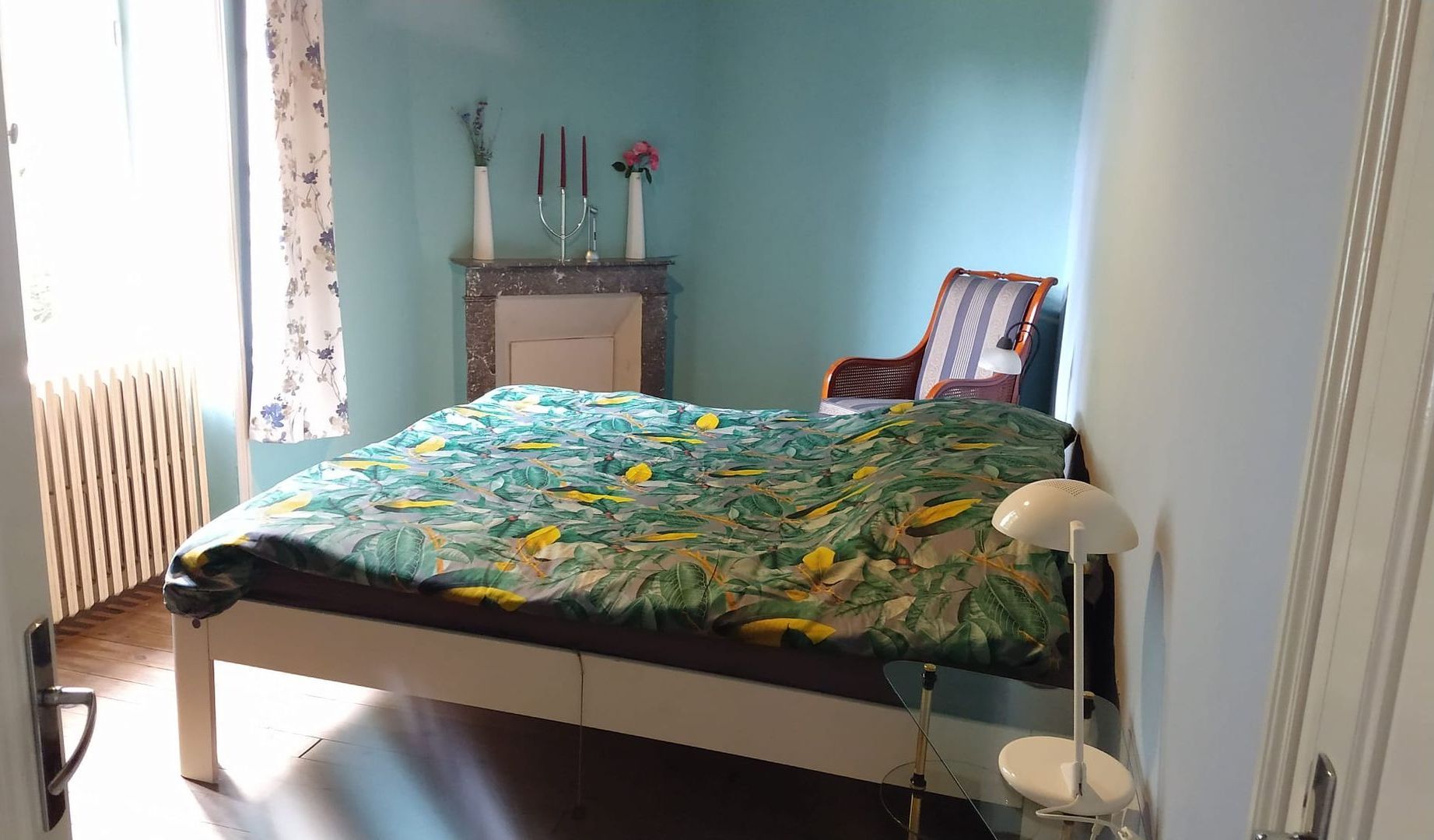A bedroom with a bed a chair and a fireplace