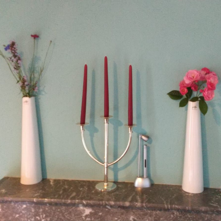 Een slaapkamer met een bed, een stoel en schouw met bloemen