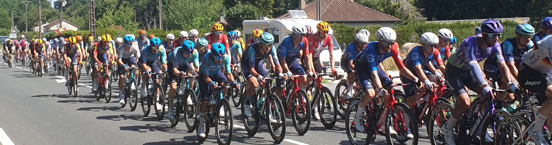 Large group of cyclists racing on a road in a line, wearing colorful jerseys and helmets