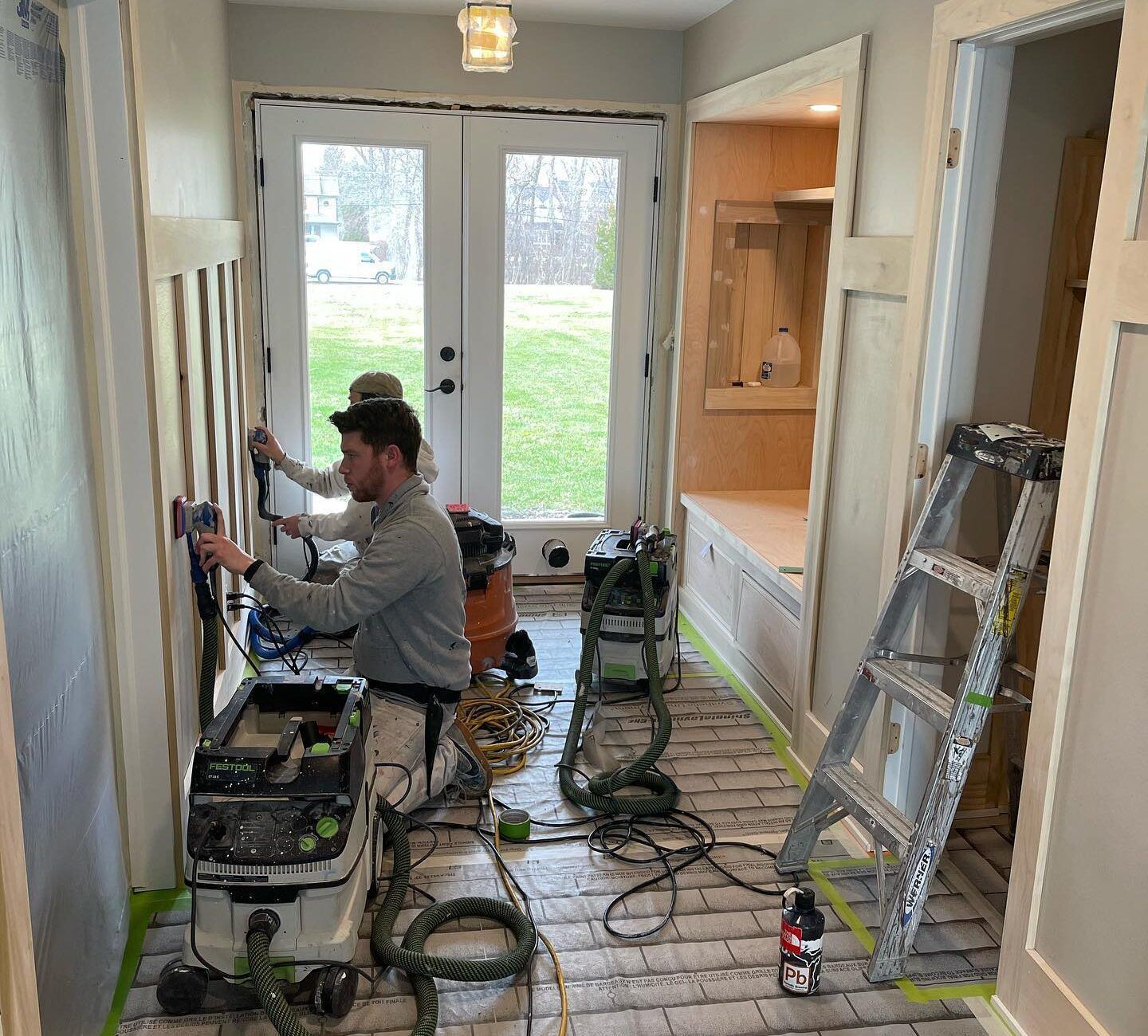 A man is working on a wall in a hallway.