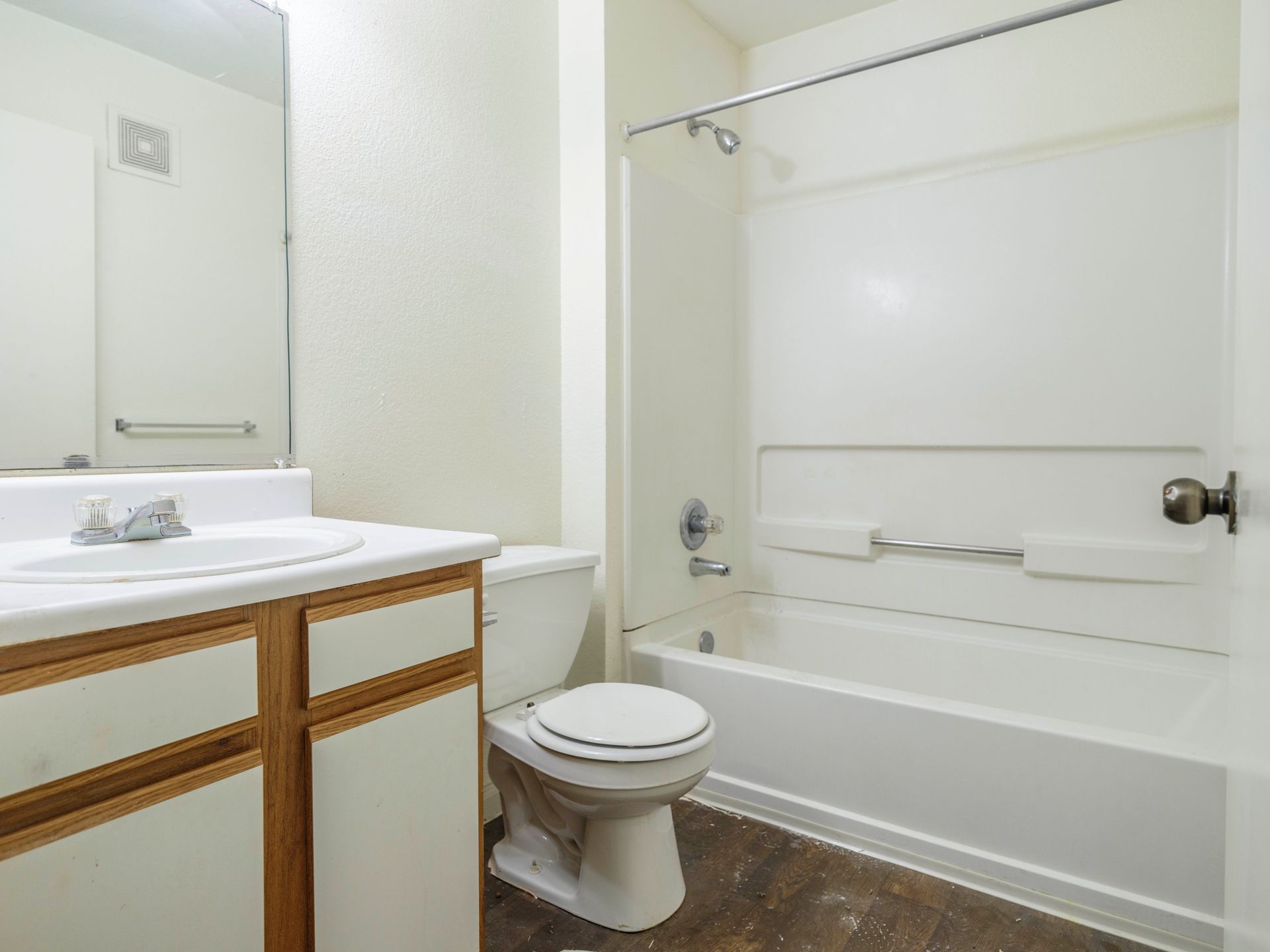 Small bathroom with vanity sink, toilet, and white tub-shower combo with beige tile floor.