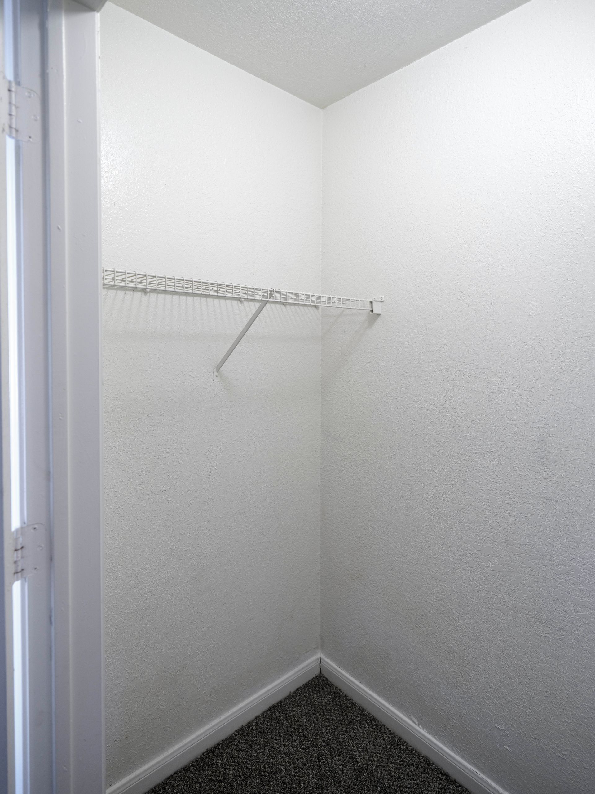 Empty white closet with wire shelf and carpeted floor