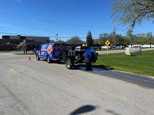 Utility truck parked on roadside with worker handling equipment and traffic cones nearby