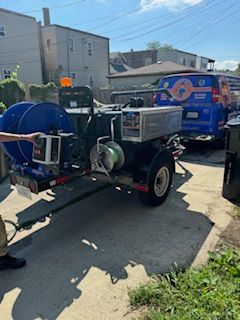 Blue utility trailers and equipment parked in a sunny alley beside buildings