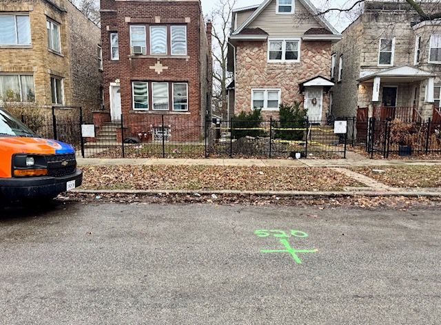 Residential street with parked truck, two brick houses, and a green parking marker on the road