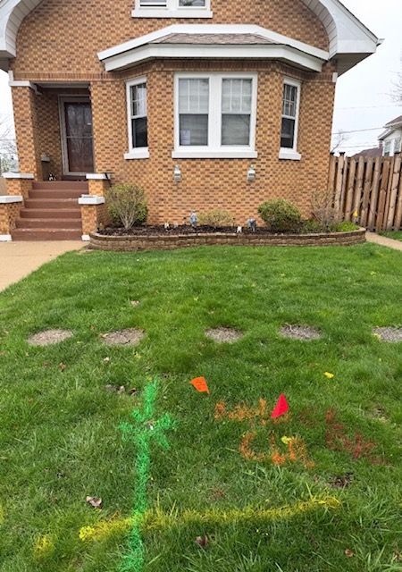 Brick house with front lawn and colorful utility marking paint in the grass
