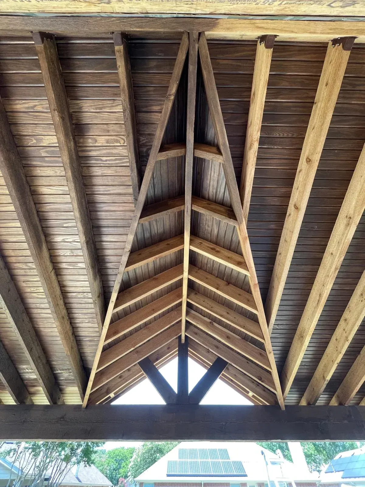 Wooden vaulted roof ceiling with exposed beams and triangular trusses seen from below