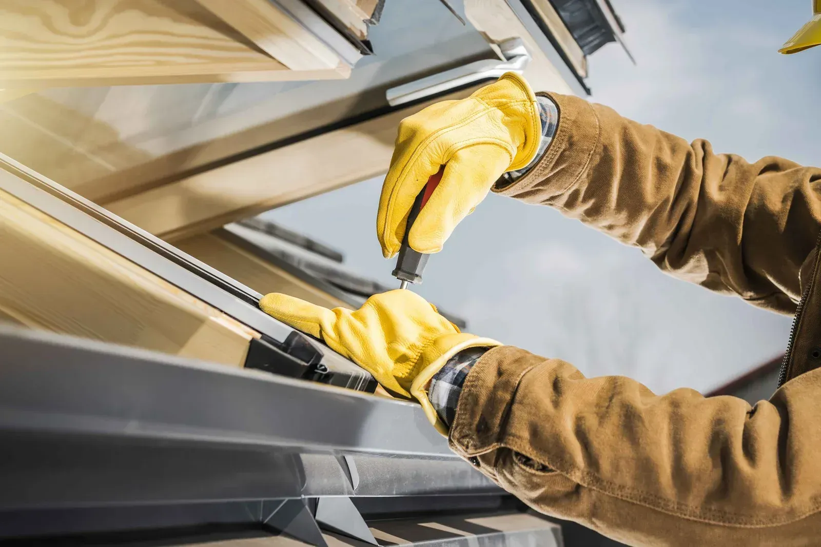 Yellow-gloved worker cleaning a skylight or window pane with a squeegee