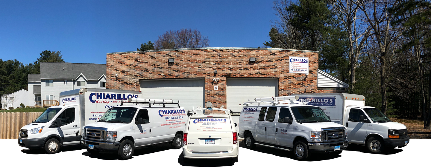 A group of white vans are parked in front of a brick building
