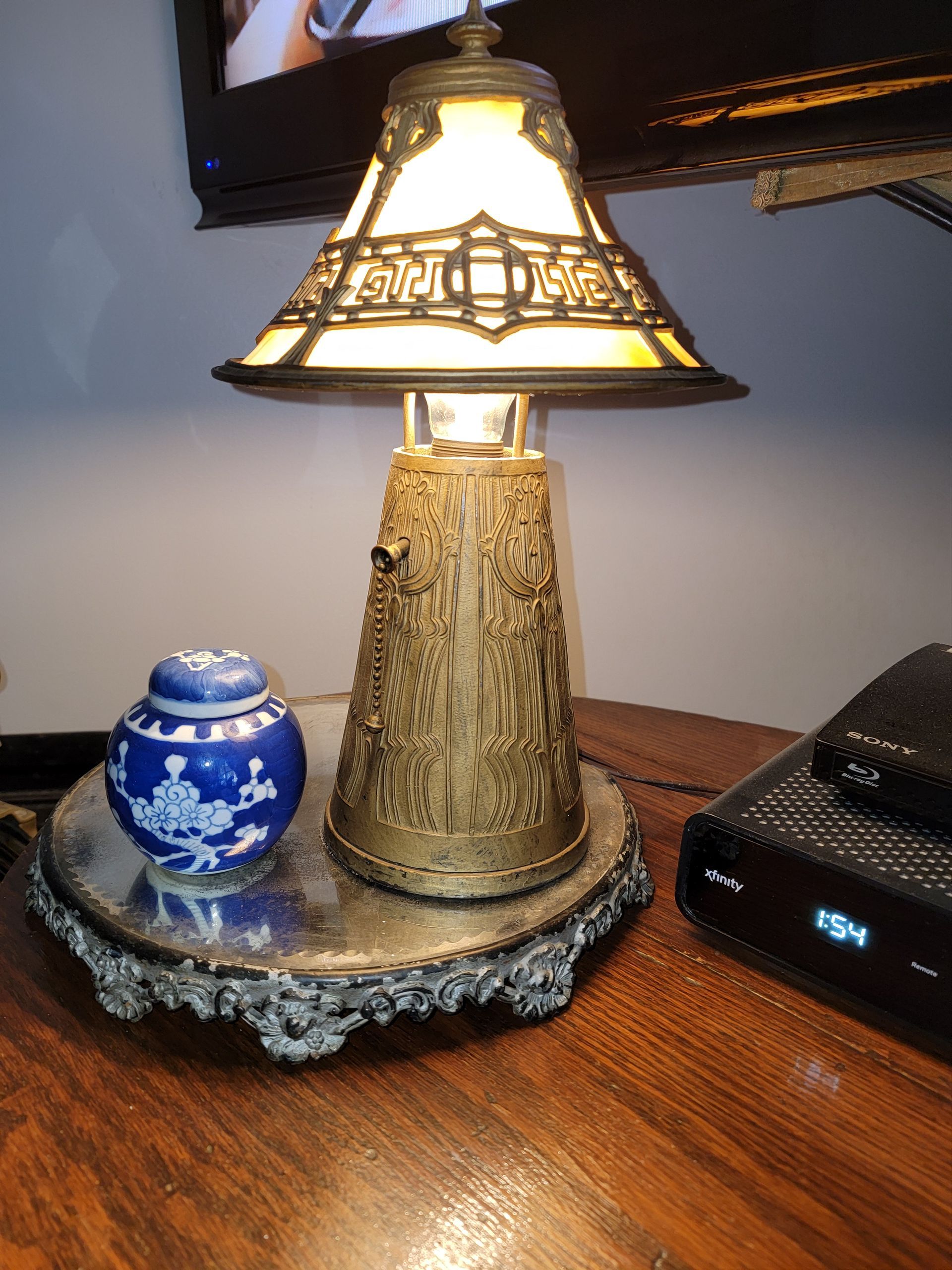 A lamp is sitting on a wooden table next to a small blue vase.
