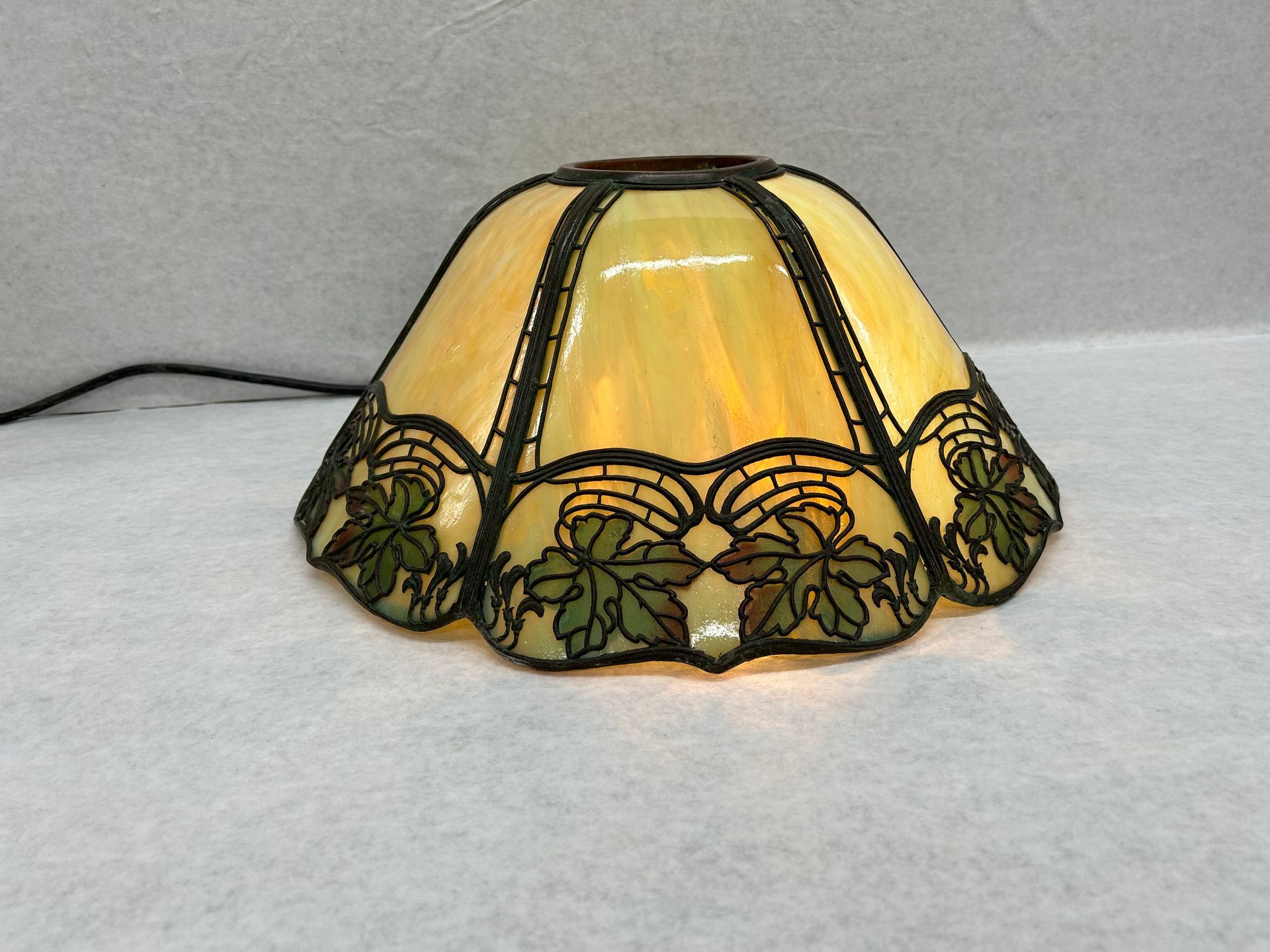 A stained glass lamp shade with leaves on it