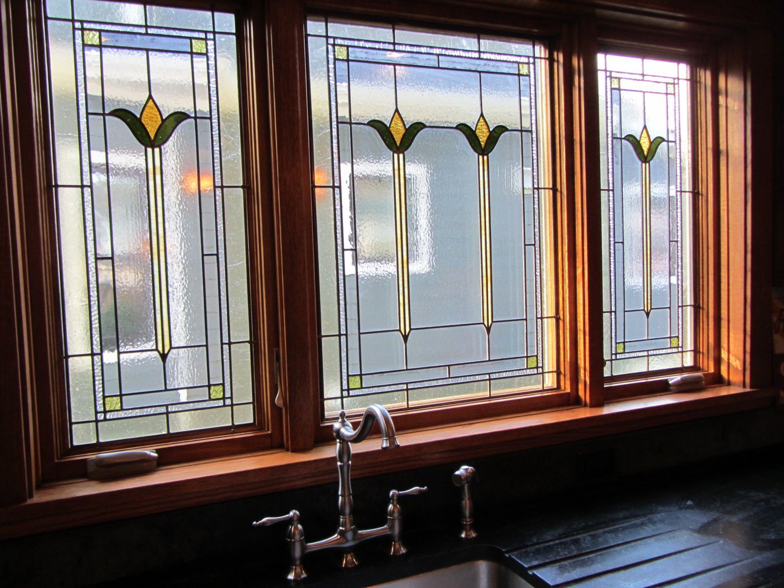 A kitchen with three stained glass windows and a sink