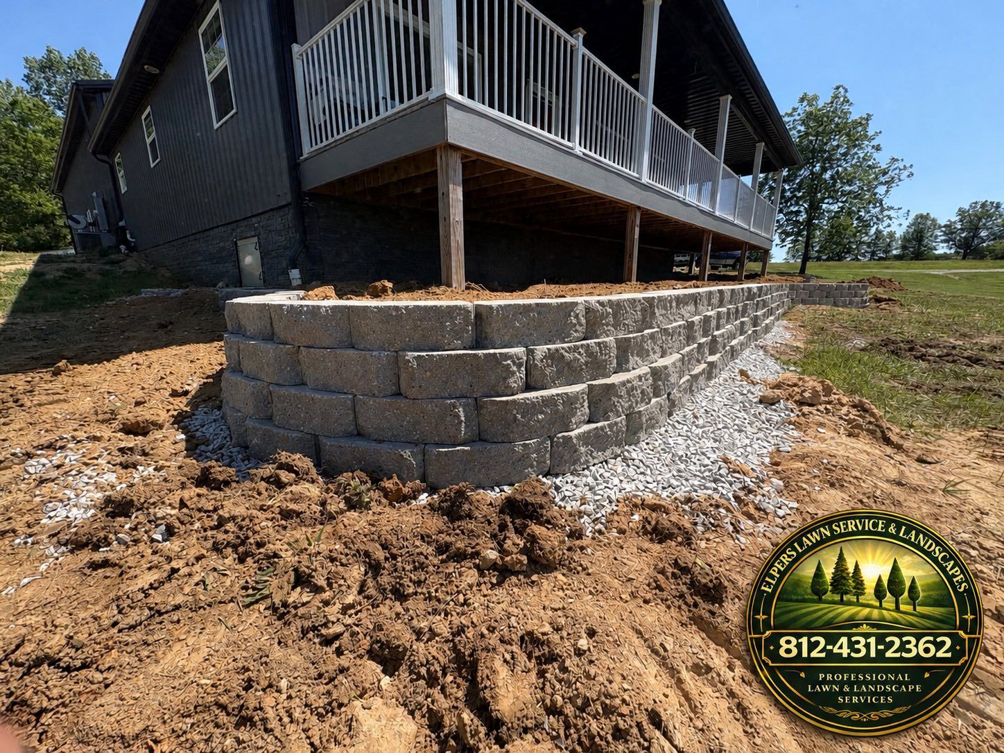 Foundation retaining wall under a house deck on a sloped, landscaped yard