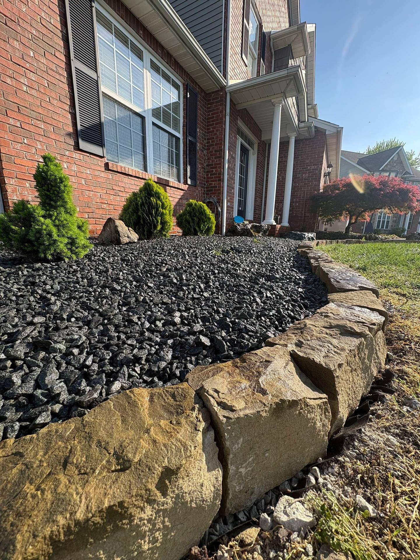 Brick house with black mulch and tan retaining wall landscaping along a walkway