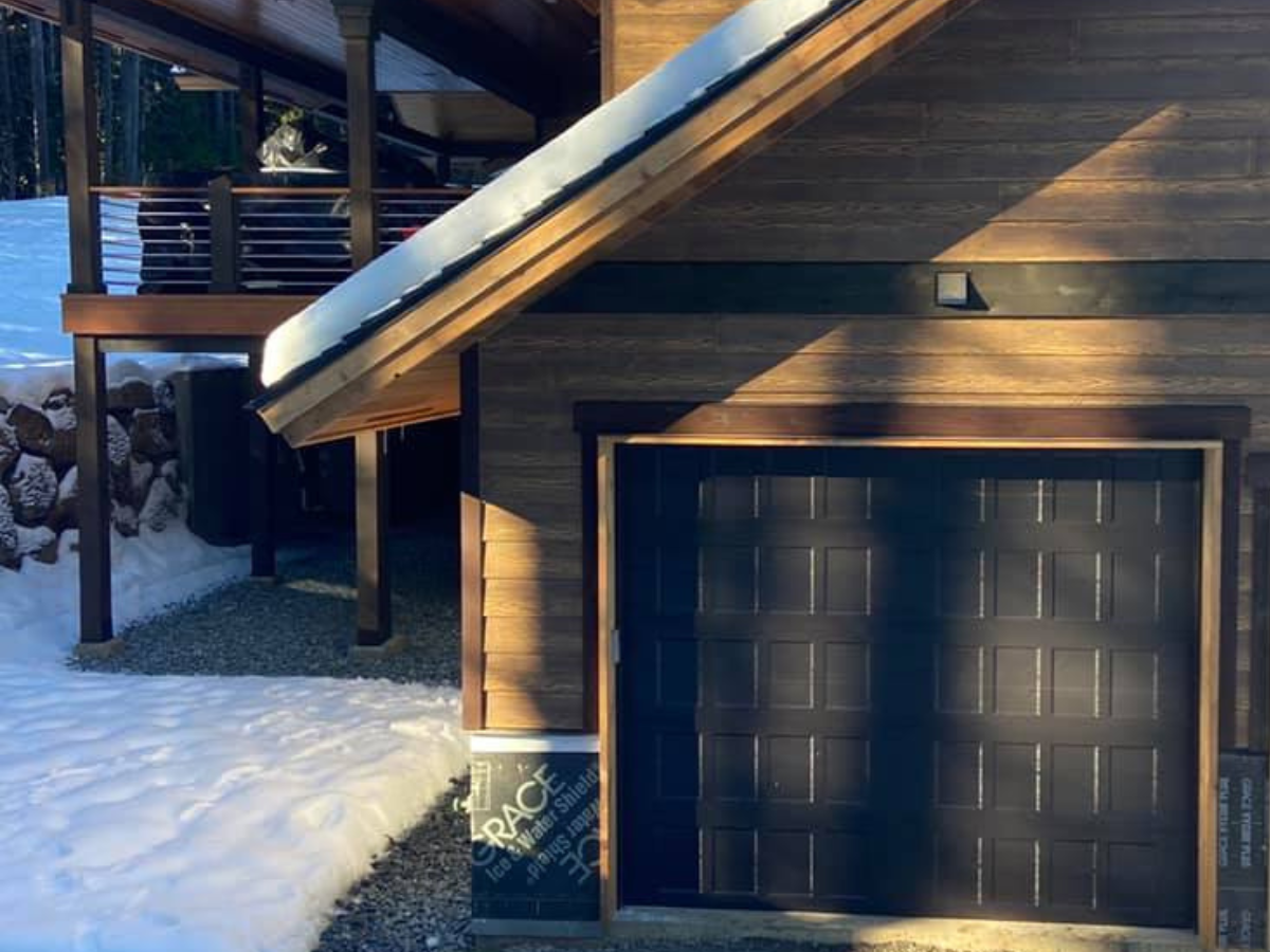 Black traditional steel garage door installation on custom home in snowy setting