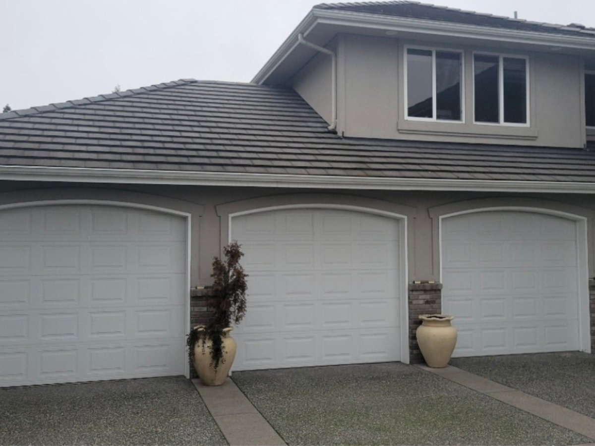 White traditional steel garage doors with arched panels installed on residential home
