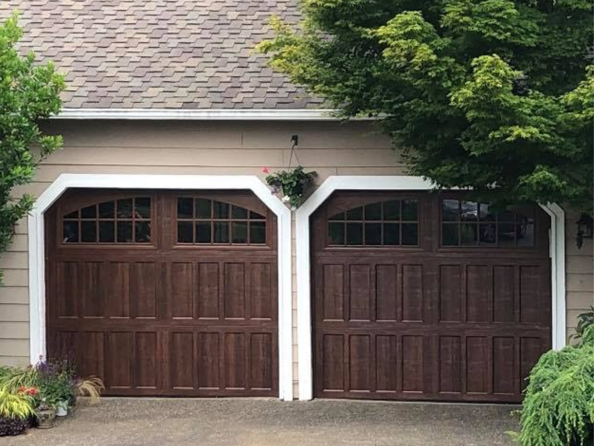 Dark wood carriage house garage doors with arched windows on a residential garage