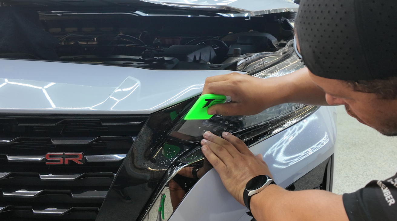 Person applying protective film to a car headlight 