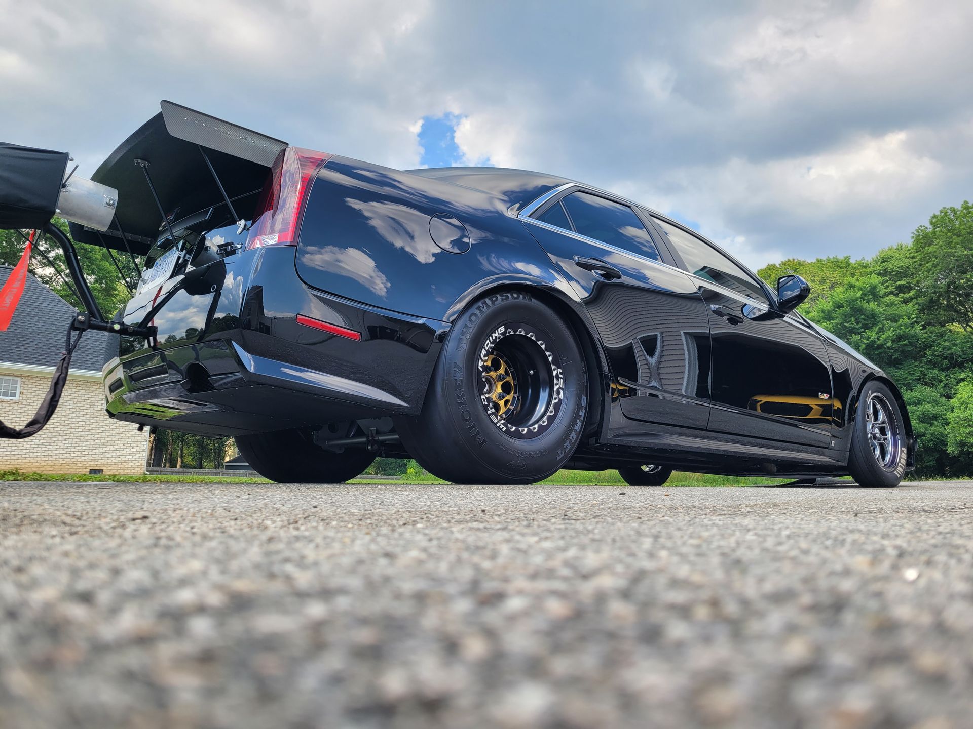 A black car is parked on the side of the road with a tow hook attached to it.