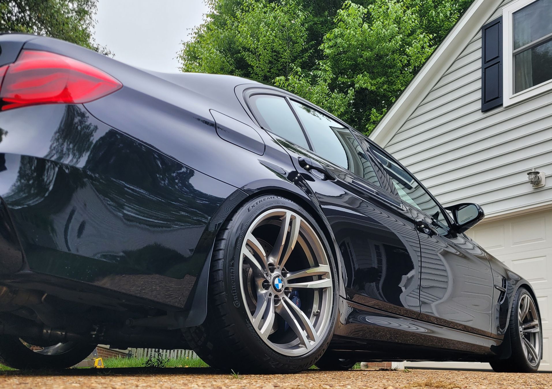 A black bmw is parked in front of a house.