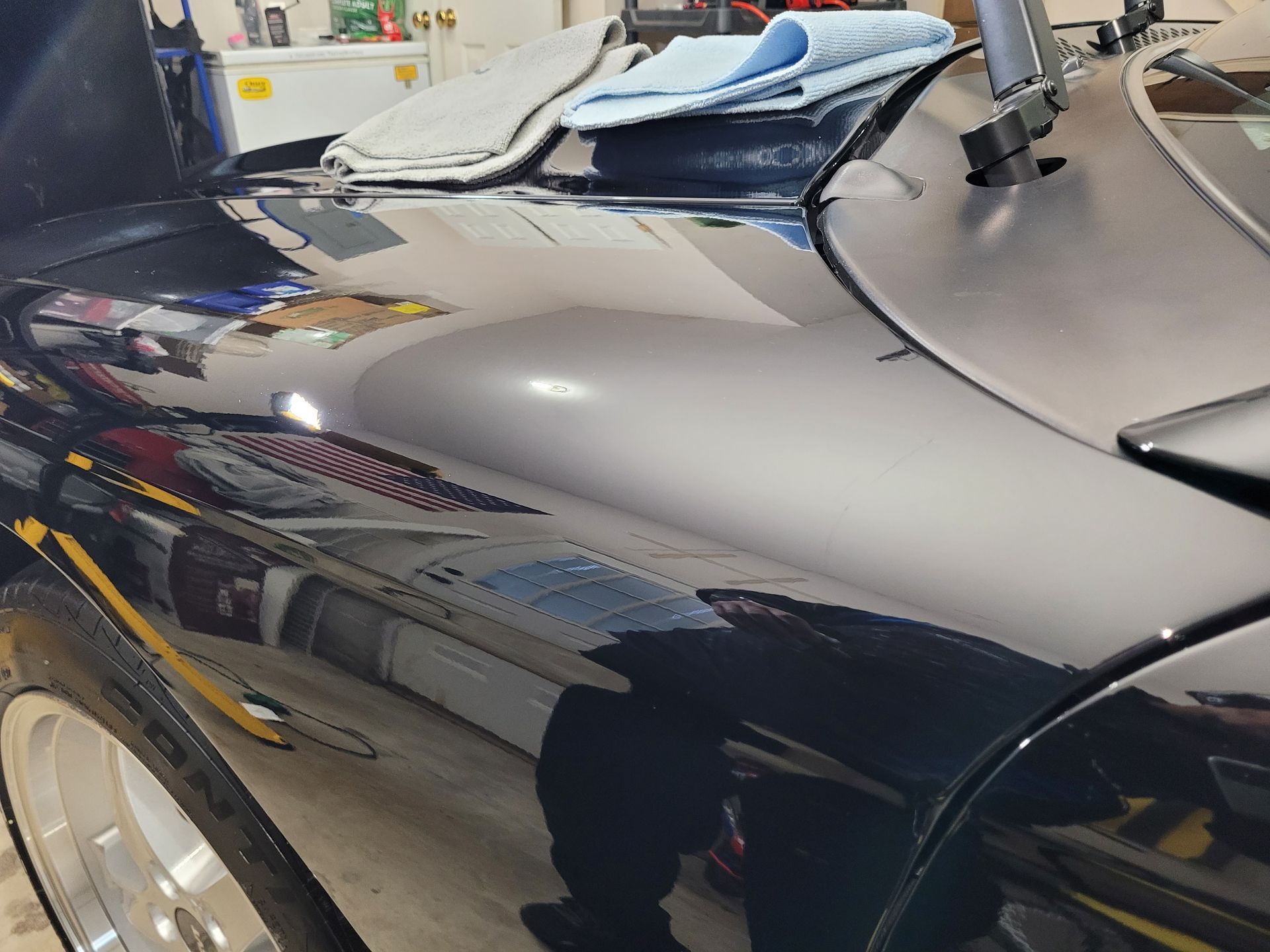 A black car is parked in a garage with the hood open