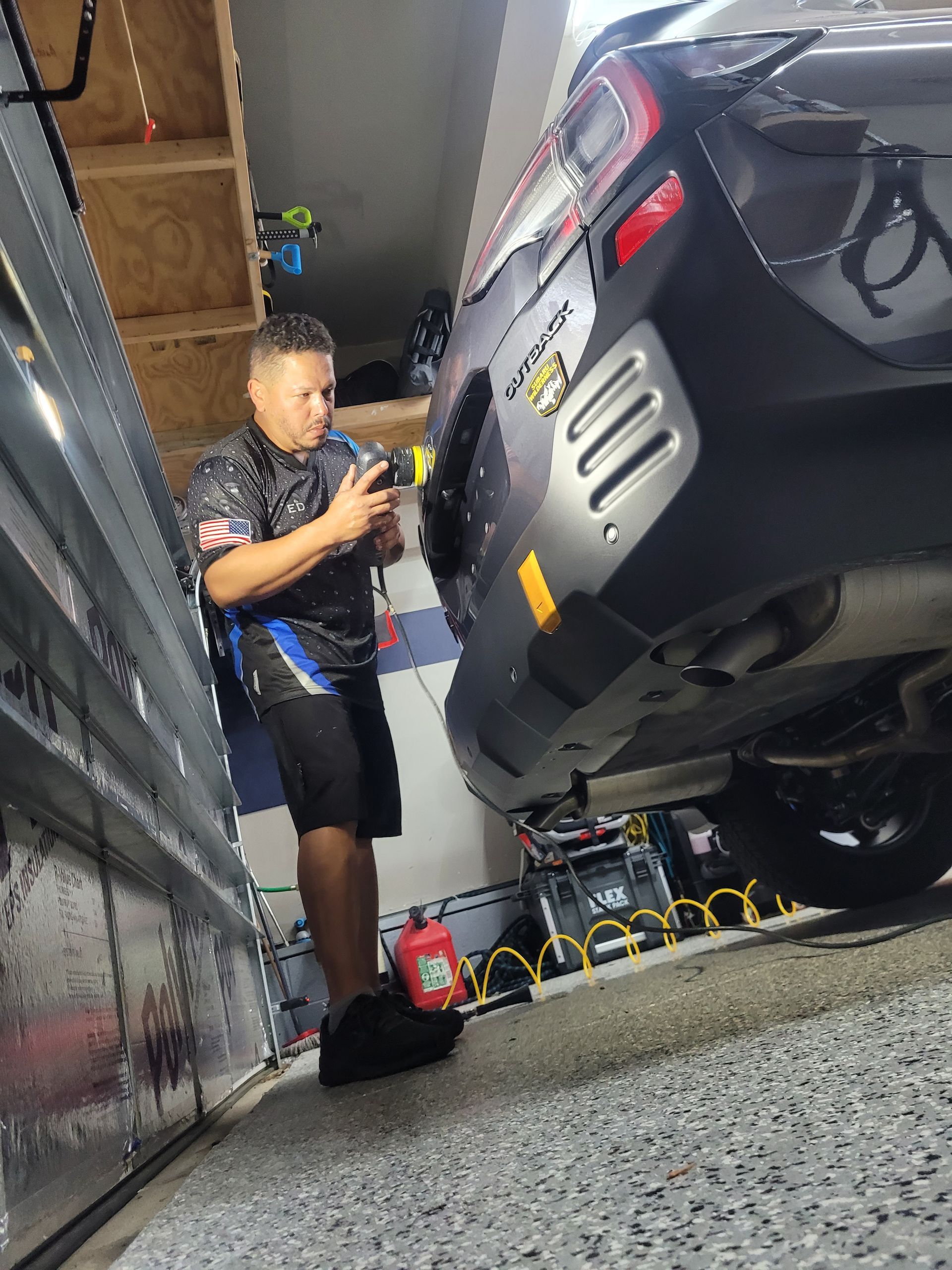 A young boy is standing next to a car in a garage.