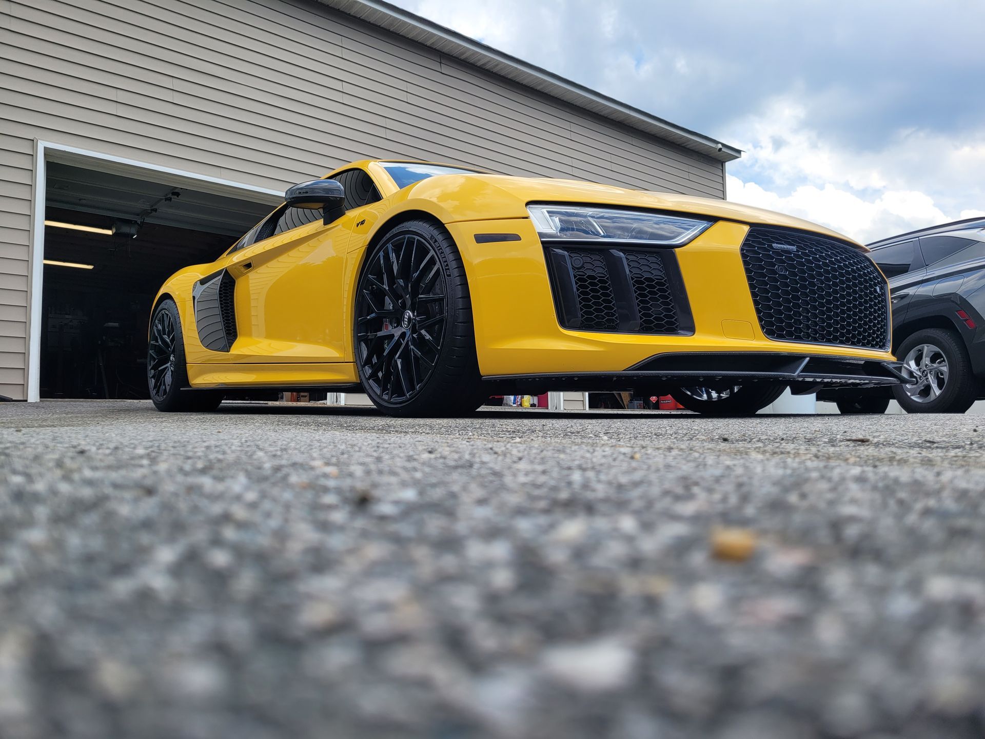 A yellow sports car is parked in front of a garage.