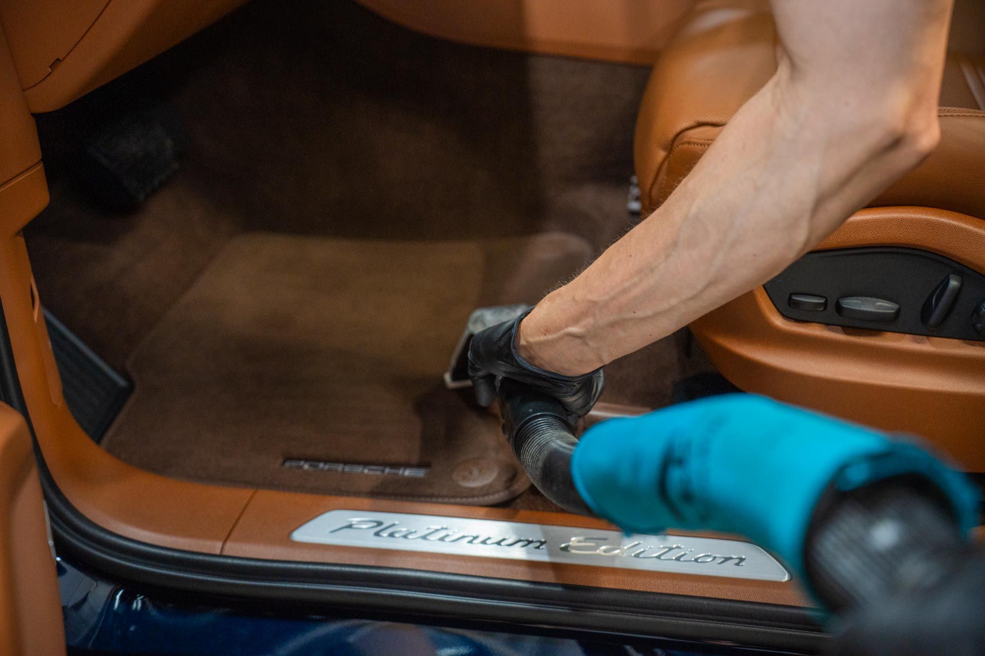 A person is vacuuming the inside of a car with a carpet extractor.