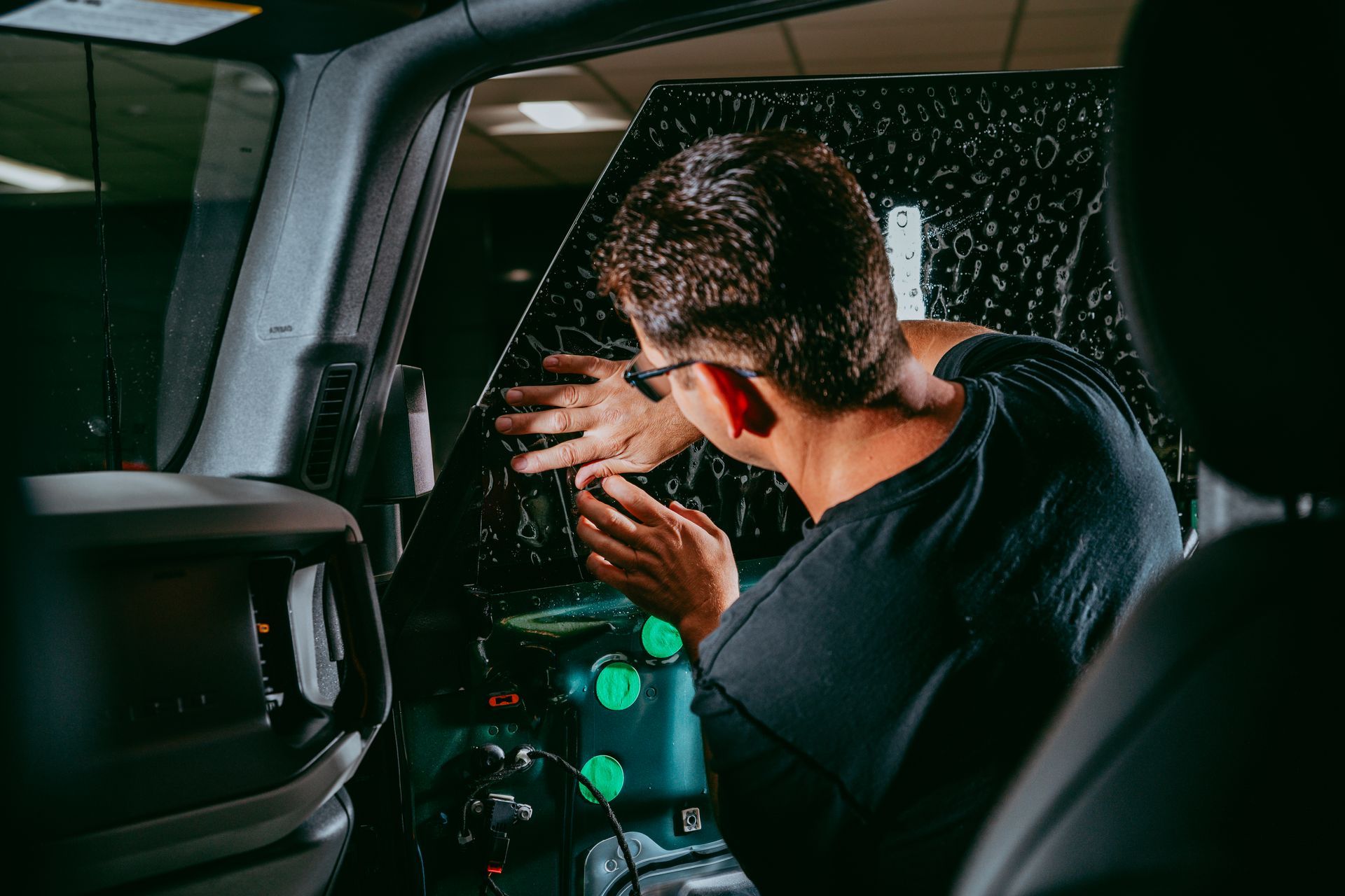 A man is applying tinted glass to the window of a car.