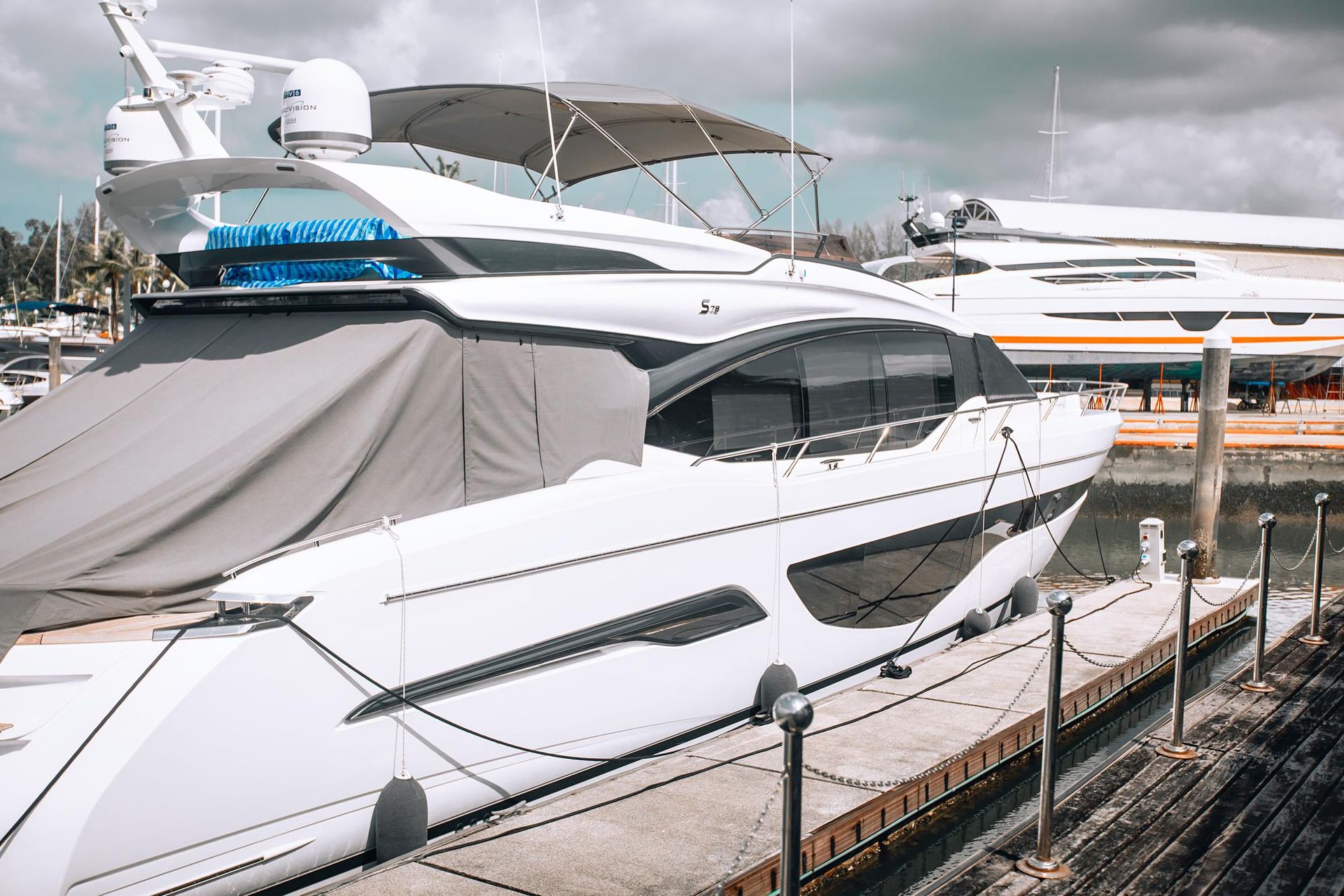 A large white yacht is docked at a marina.