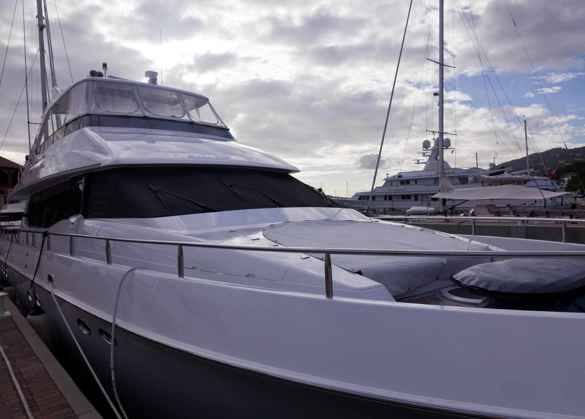 A large white yacht is docked in a marina.