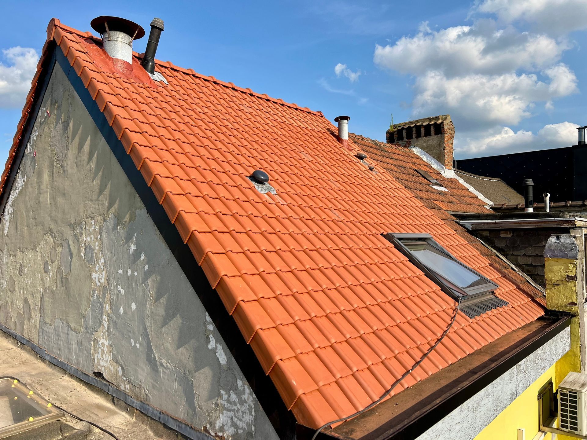Orange tile roof with skylight and chimneys, installed by a local roofer in Pooler, GA.