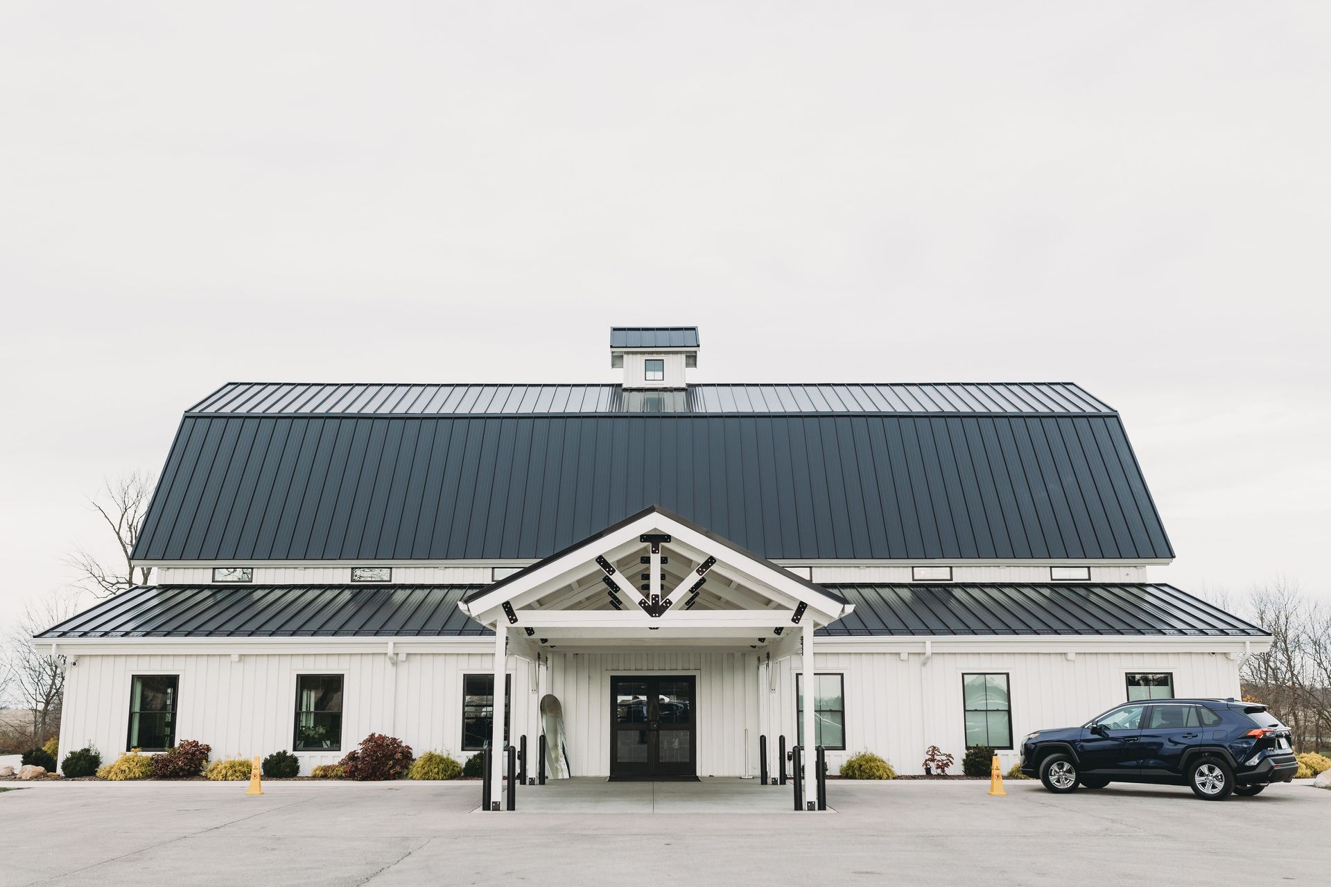 White building with a dark blue roof and a parked car in front