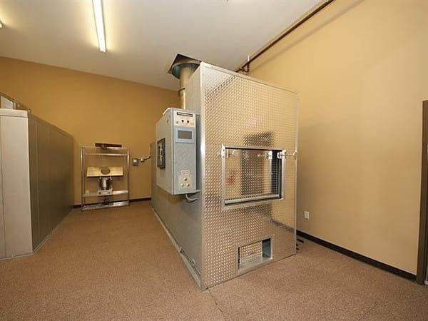 Small industrial room with a fenced metal machine, beige walls, and a sink on the left