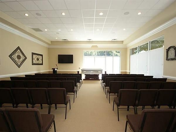 Empty conference room with rows of chairs facing a podium and wall-mounted screen
