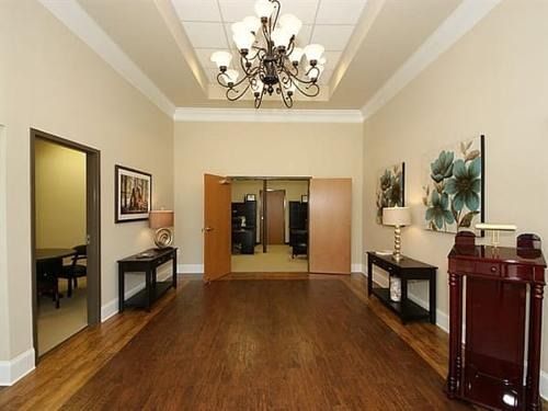 Elegant hallway with wood floors, chandelier, side tables, and open double doors at the far end