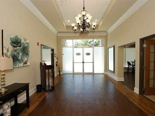 Empty foyer with hardwood floors, chandelier, and glass double doors leading outside.