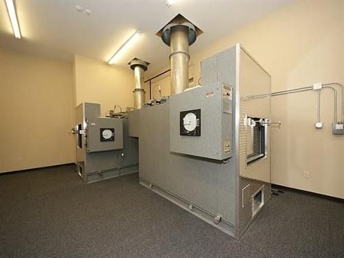 Large industrial HVAC units in a clean utility room with gray ducts and beige walls