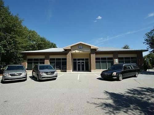 Small commercial building with parked cars in front on a sunny day