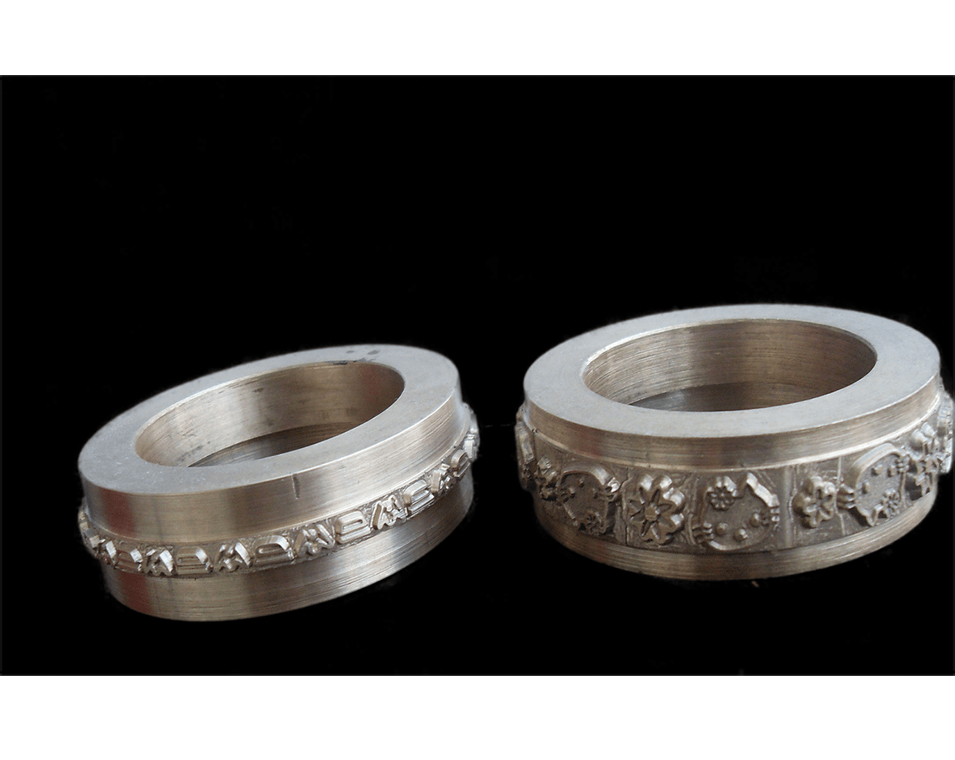 Dos anillos de plata con motivos florales grabados.