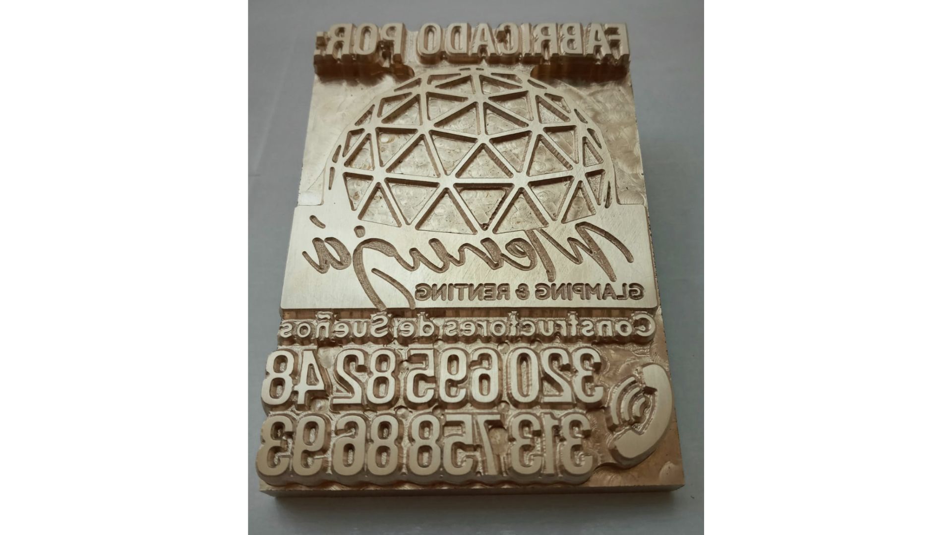 Un sello de latón con texto y diseño de cúpula geodésica para una empresa de construcción.