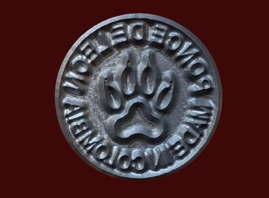 Emblema de metal estampado con huella de pata de oso rodeado de texto: 