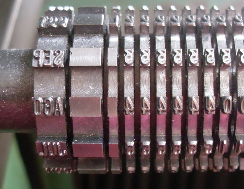 Primer plano de una rueda de sello numerador de metal que muestra varios números y letras utilizados para marcar.